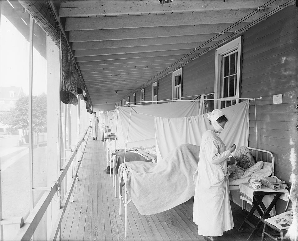 Influenza ward at Walter Reed Hospital, Washington D.C., 1918, with rows of beds and a nurse wearing a mask