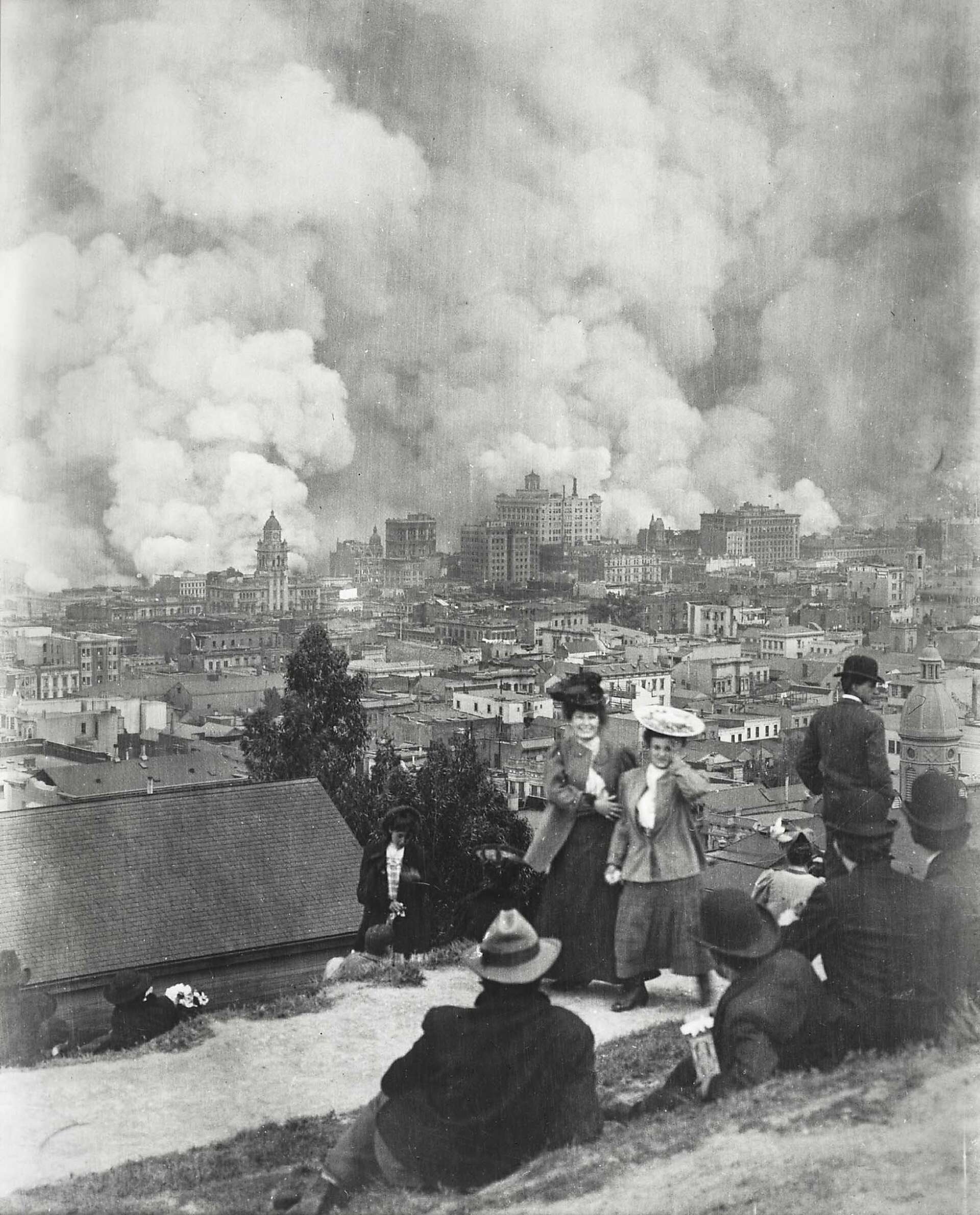 Two young women posing for Arnold Genthe in front of the fire consuming San Francisco, April 18, 1906