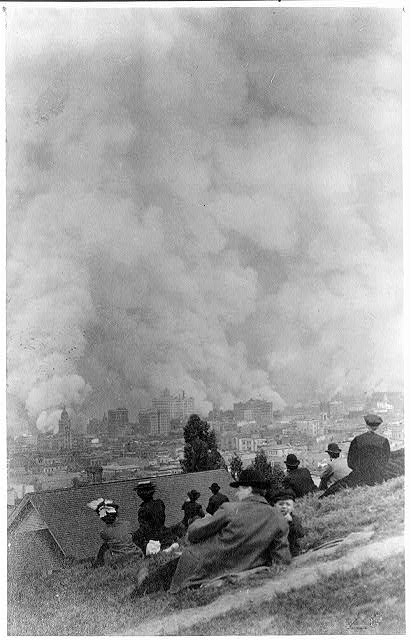 Spectators sitting on a hillside watching the fires consume San Francisco after the 1906 earthquake